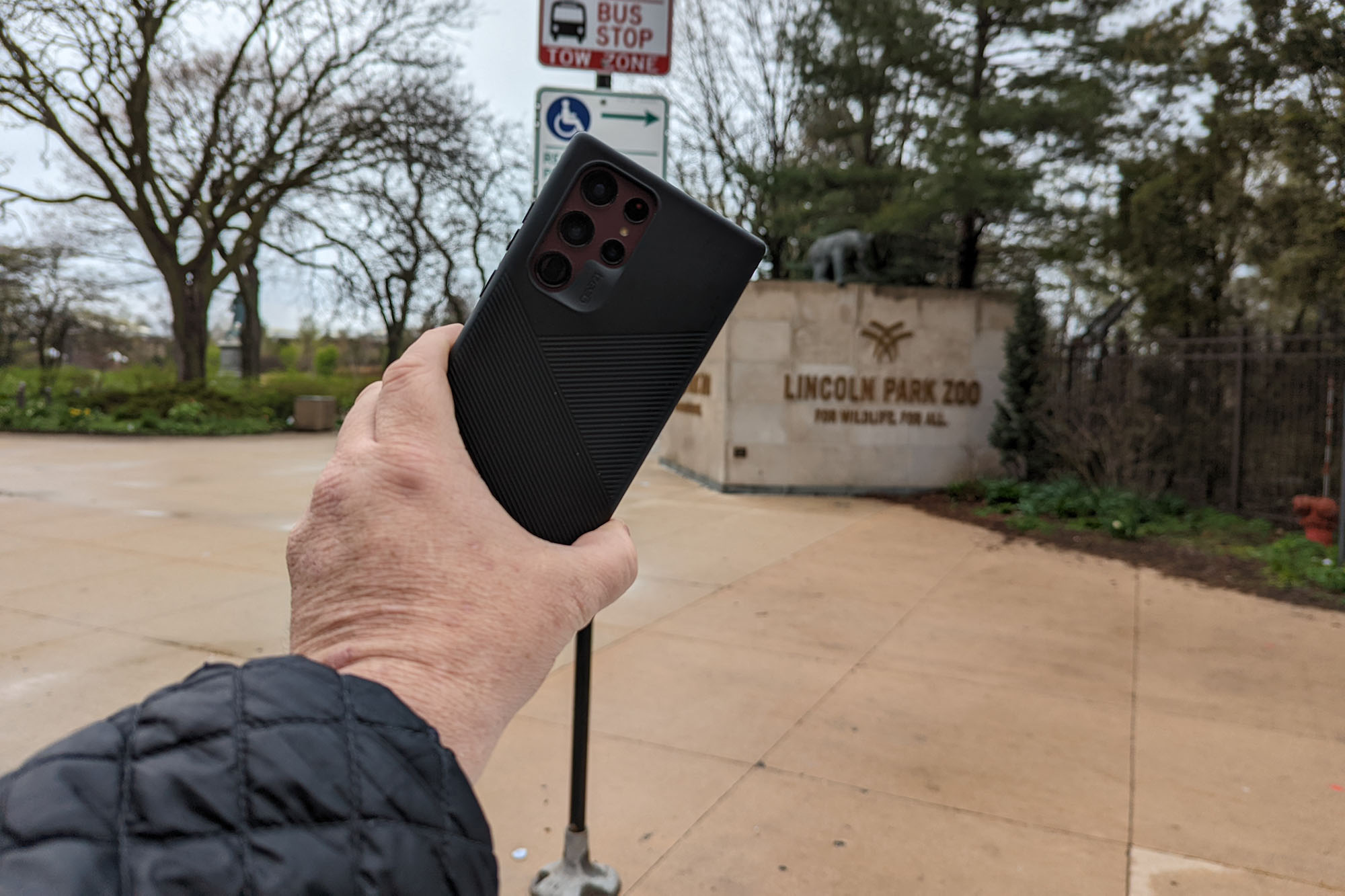 A man holds the Samsung Galaxy S22 Ultra with the Lincoln Park Zoo in the background