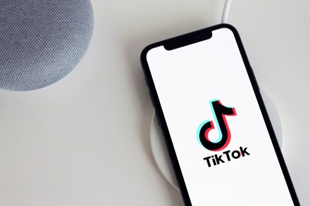 TikTok on a white smartphone screen all on a white table