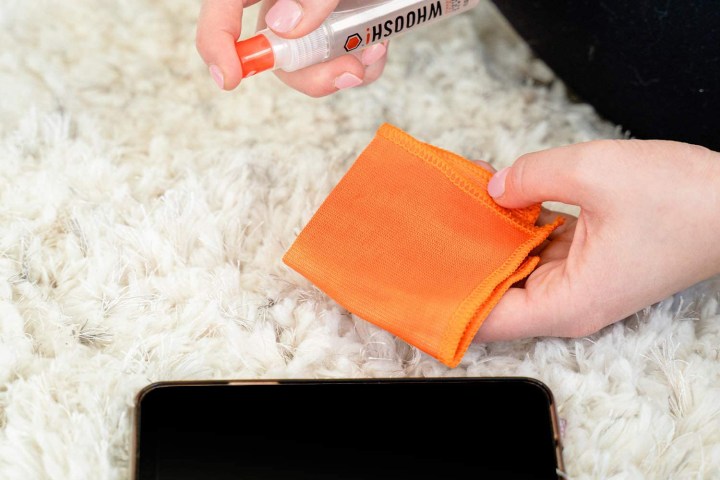 Person using WHOOSH! Screen Cleaner Kit to clean an iPhone. 