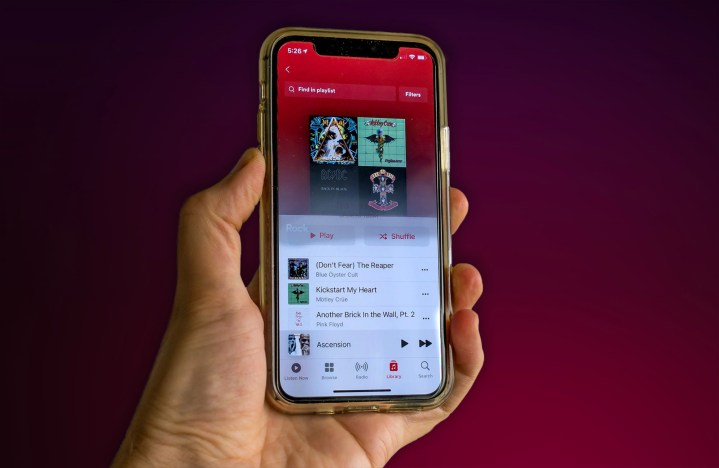 A person holds an iPhone 11 with the Apple Music app open.