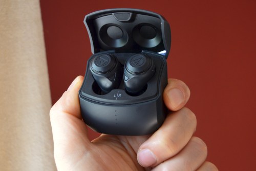 Hand holding Audio-Technica ATH-CKS50TW wireless earbuds in their case.