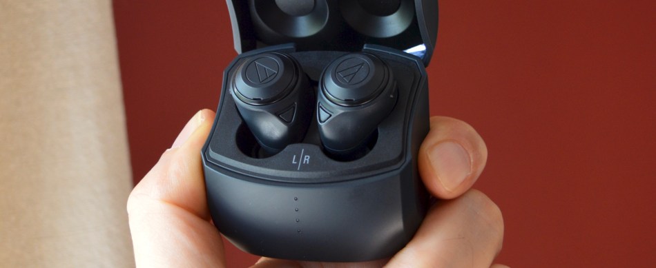 Hand holding Audio-Technica ATH-CKS50TW wireless earbuds in their case.