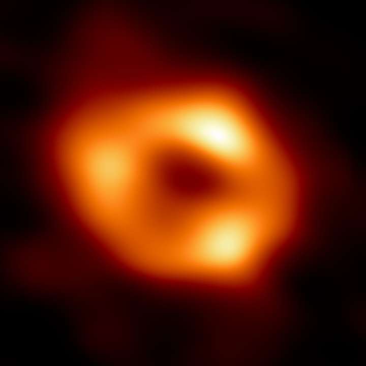 Esta é a primeira imagem de Sagitário A* (ou Sgr A* para abreviar), o buraco negro supermassivo no centro da nossa galáxia.  É a primeira evidência visual direta da presença deste buraco negro.  Ele foi capturado pelo Event Horizon Telescope (EHT), um conjunto que conectou oito observatórios de rádio existentes em todo o planeta para formar um único telescópio virtual do “tamanho da Terra”.  O telescópio recebeu o nome do “horizonte de eventos”, o limite do buraco negro além do qual nenhuma luz pode escapar.