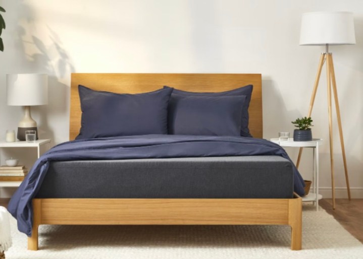 This is a Casper mattress on a wood bed frame in a bright bedroom.