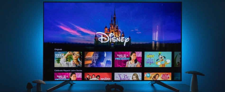 The Disney+ app on a TV screen while blue lights illuminate the wall behind.