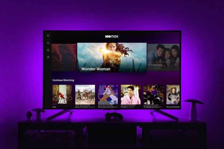 Aplicación HBO Max en la pantalla de un televisor mientras luces violetas iluminan la pared de atrás.