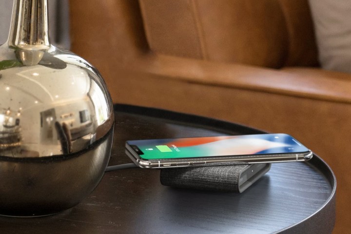 iOttie ION Wireless Mini Fast Charging Pad on table charging an iPhone.