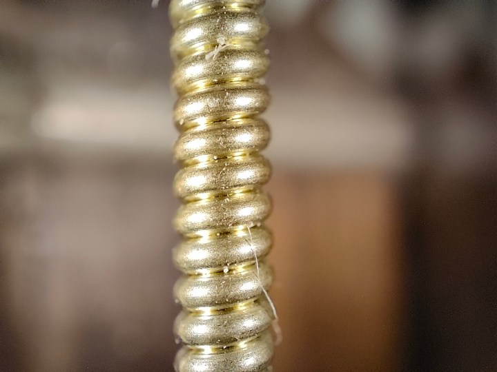 Vista macro di una corda di mi basso di una chitarra acustica in bronzo fosforoso fotografata con la fotocamera del microscopio di Realme GT 2 Pro.