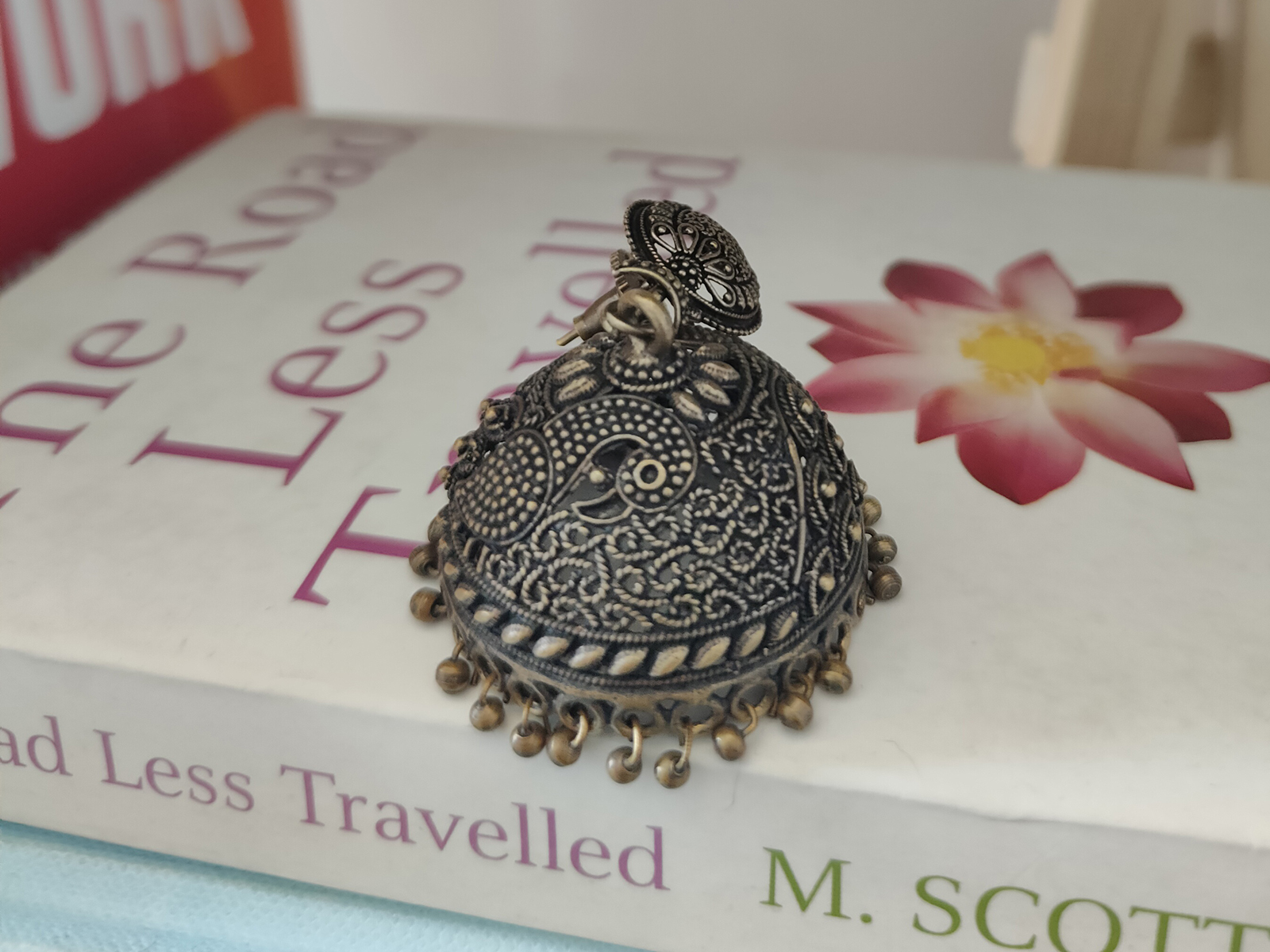 A German silver earring on The Road Less Travelled by psychologist M. Scott Peck photographed with the Realme GT 2 Pro's primary