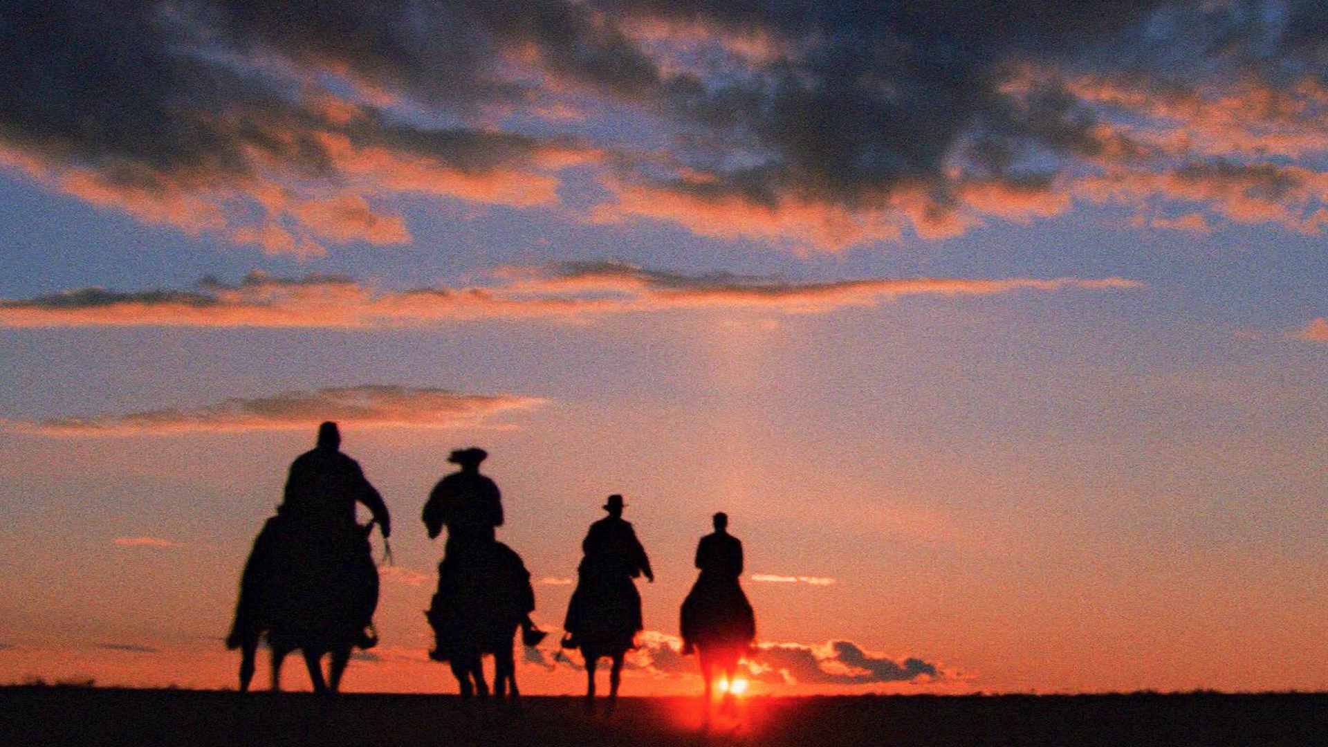 Homens cavalgam ao pôr do sol em Indiana Jones e a Última Cruzada 