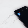 Смартфон со значком приложения Facebook на фоне белого мрамора.