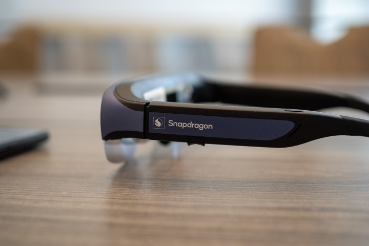 Lunettes intelligentes Qualcomm Snapdragon reference XR placées latéralement sur une table à côté d'un smartphone.