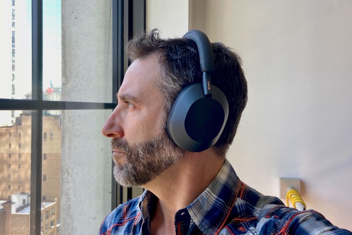 Sony WH-1000XM5 kablosuz kulaklık takan adamın yan görünümü.