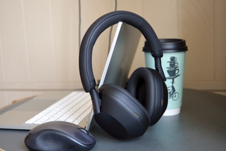 笔记本电脑、鼠标和咖啡杯旁边的索尼 WH-1000XM5 无线耳机。