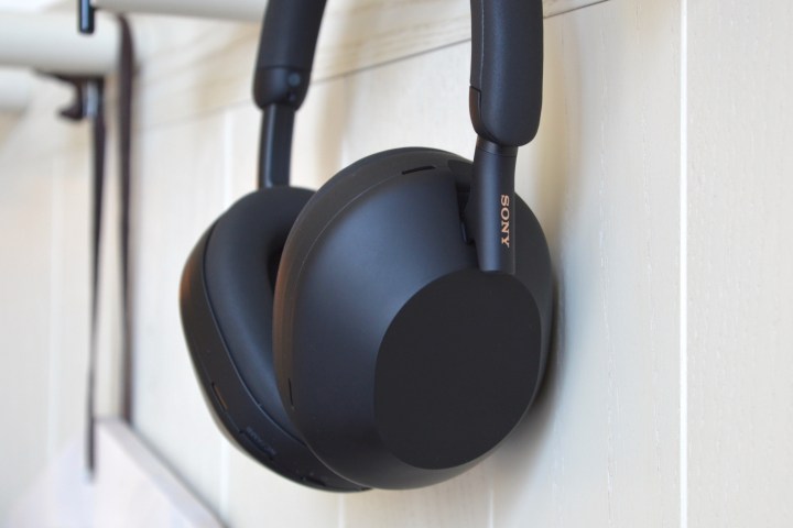 Sony WH-1000XM5 wireless headphones hanging on a wall hook.
