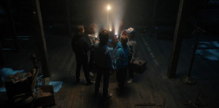 Le casting de Stranger Things tient des lumières dans un grenier sombre, réunis en cercle.