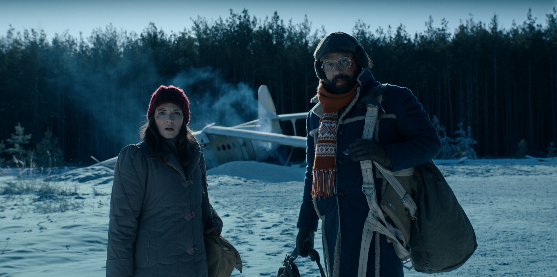 Winona Ryder e Brett Gelman estão na frente de um avião caído na neve em uma cena de Stranger Things 4.