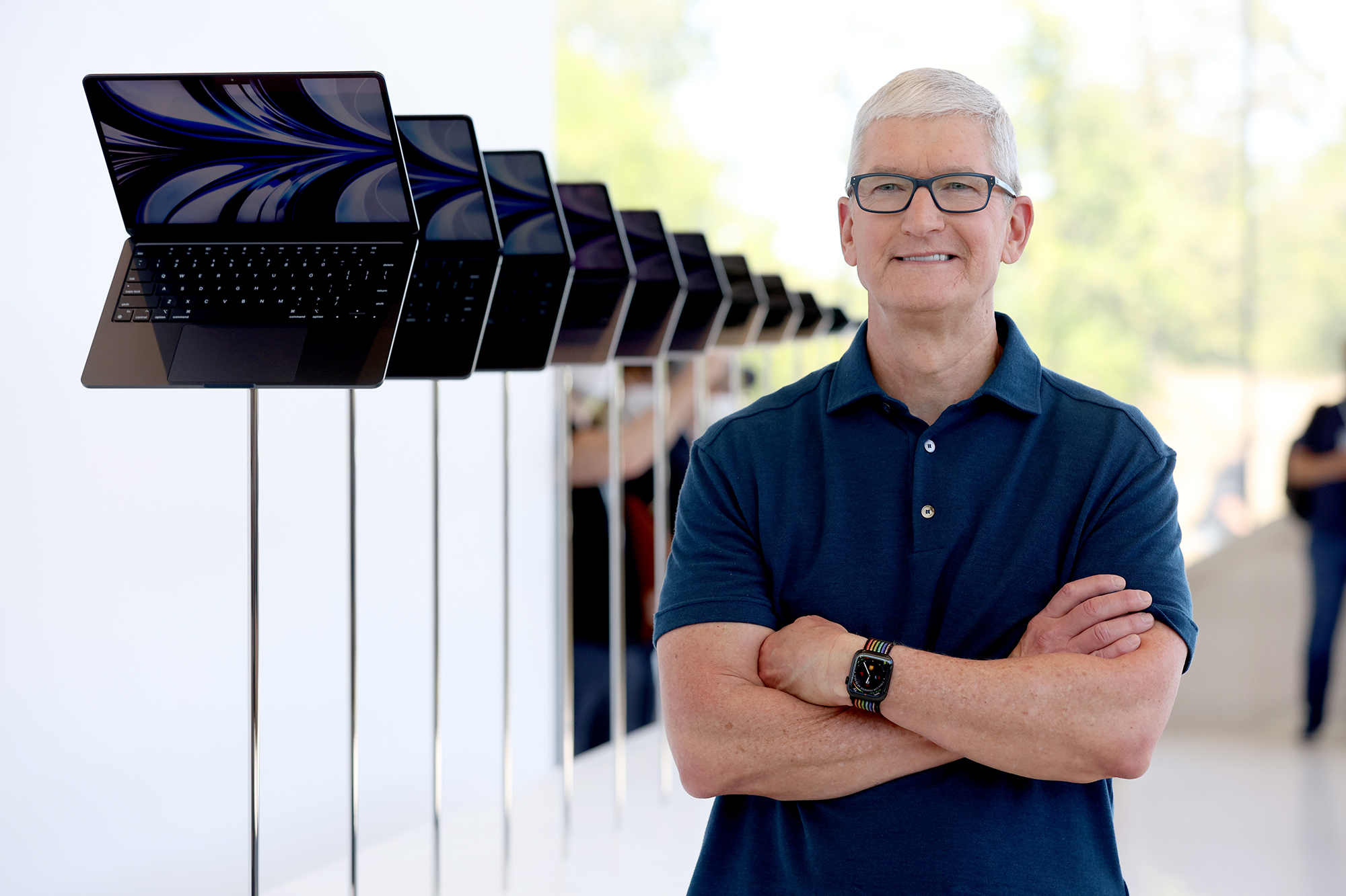 O CEO da Apple, Tim Cook, olha para uma exibição do novo laptop MacBook Air redesenhado durante a WWDC22
