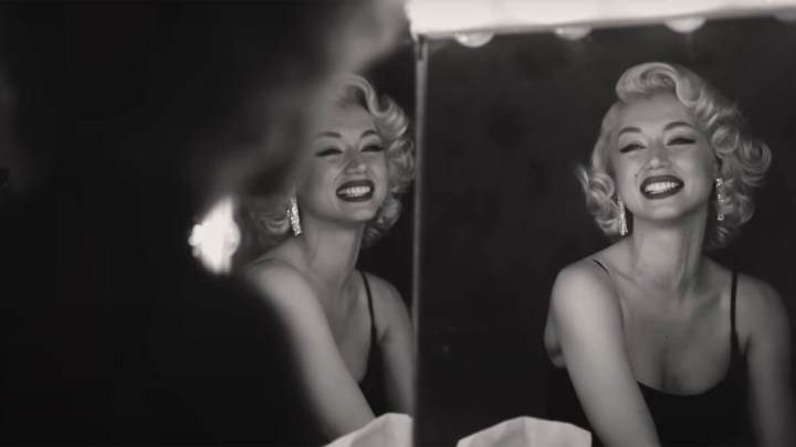 Ana de Armas as Marilyn Monroe smiling at a mirror in Blonde.