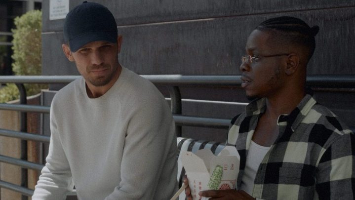 Cam Gigandet sitting on a bench next to someone in a scene from Blowback.