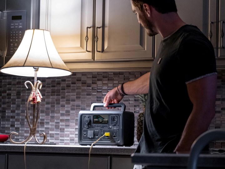 Un uomo accende una lampada in una cucina durante un'interruzione di corrente con un Bluetti EB3A.