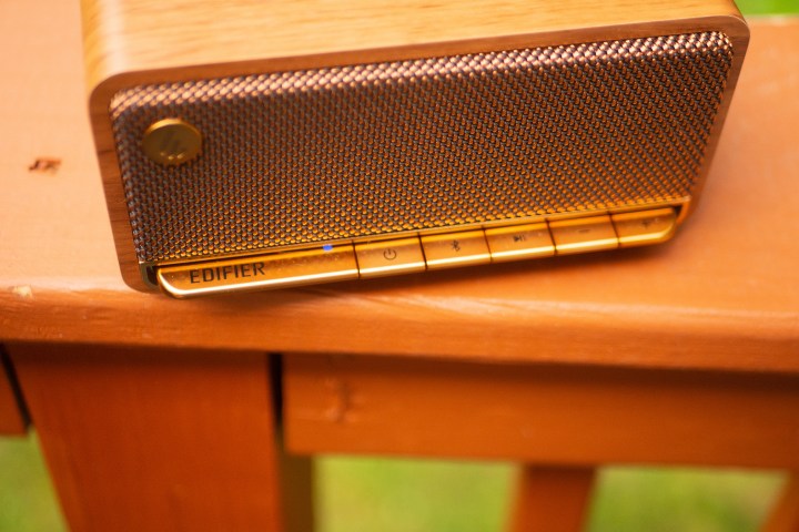The Edifier MP230 speaker is sitting on a railing on a porch outside.