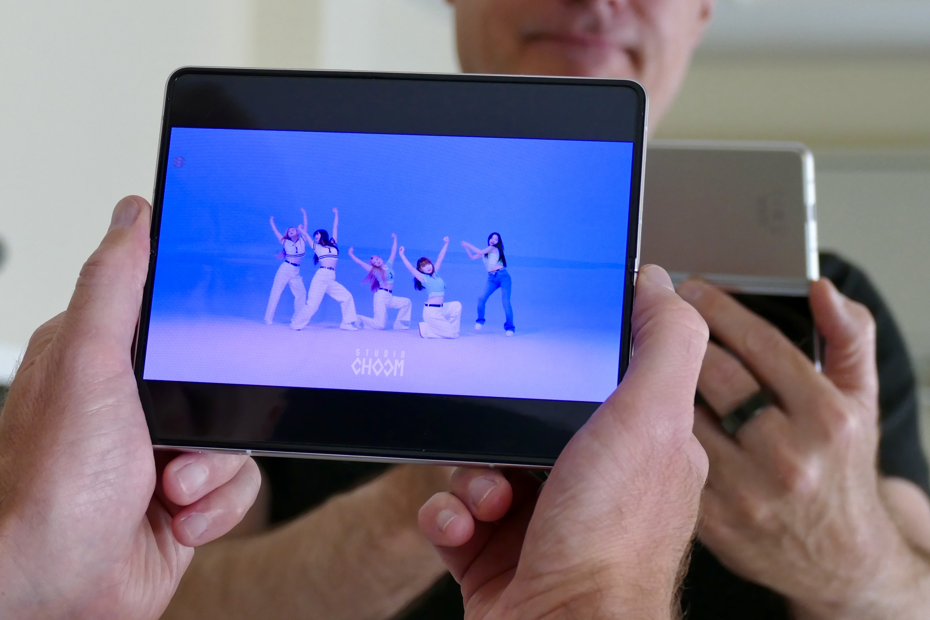 Galaxy Z Fold 3 segurado por um homem enquanto reproduz vídeo na tela aberta.