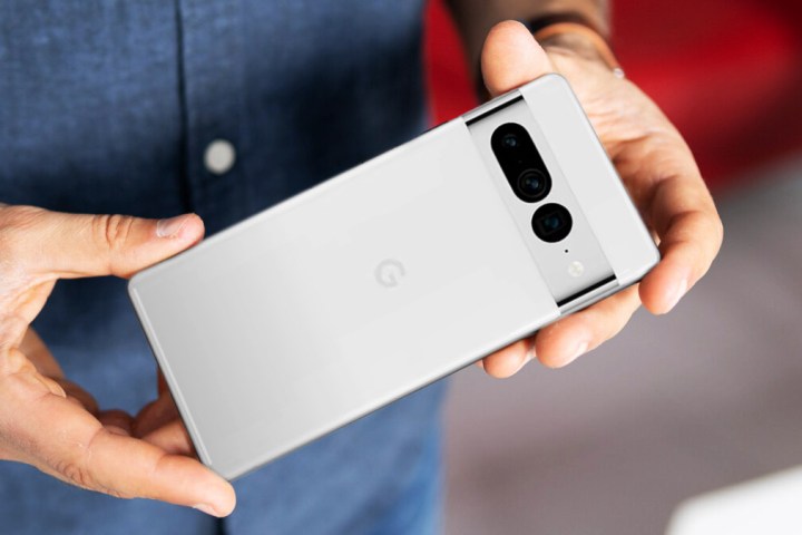 Ein Mann hält ein weißes Google Pixel 7 Pro in seinen Händen.
