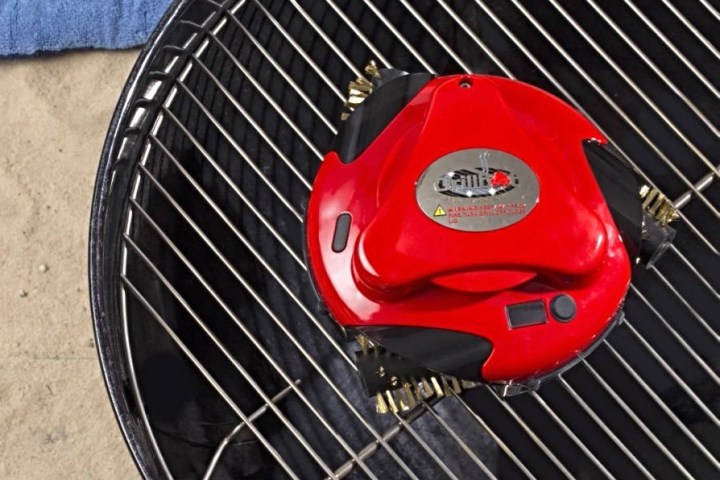 Grillbot automatic grill cleaner in red on a grill