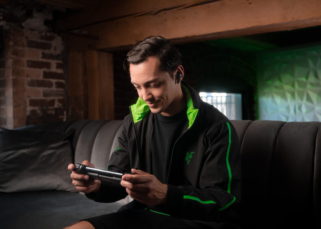 A man plays a Razer Kishi V2 on his couch.