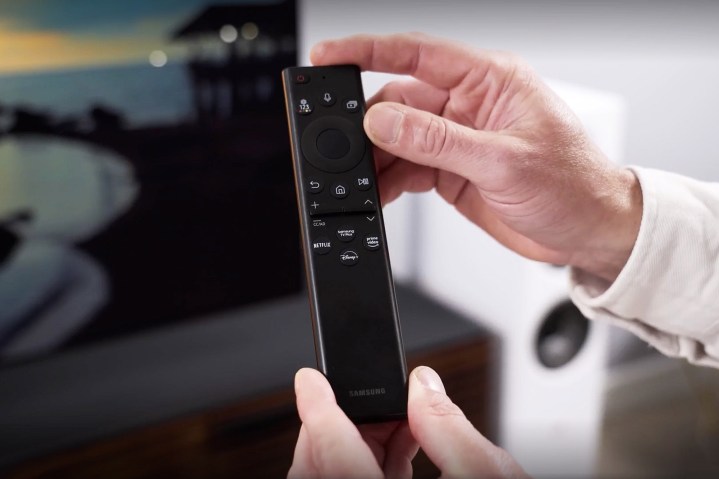 A man holds the Samsung S95B OLED remote.