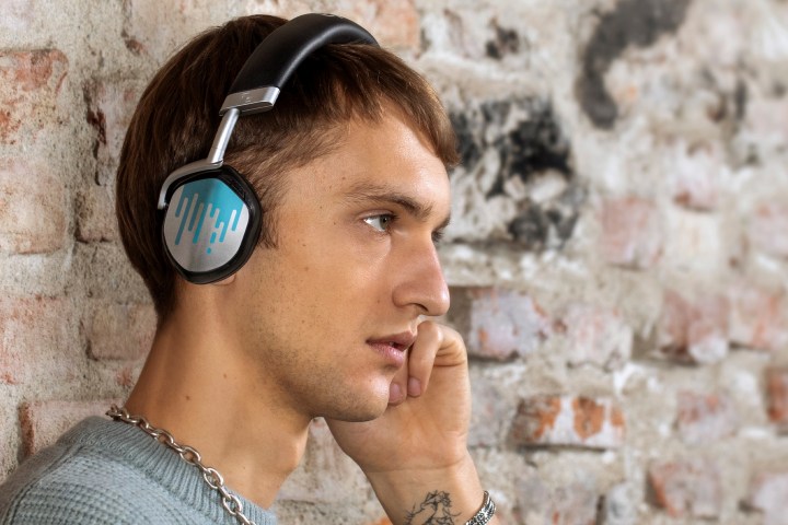 A man is wearing designer, silver-and-blue V-MODA S-80 headphone and interacting with them.