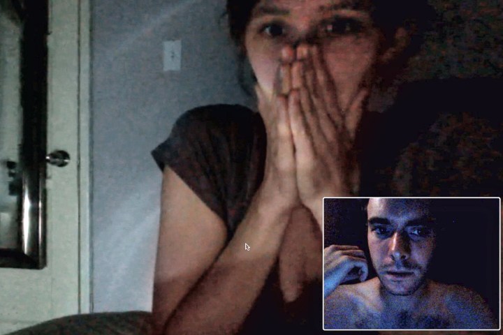 Una donna è seduta su una chiamata in webcam che si copre la bocca dal film VHS.
