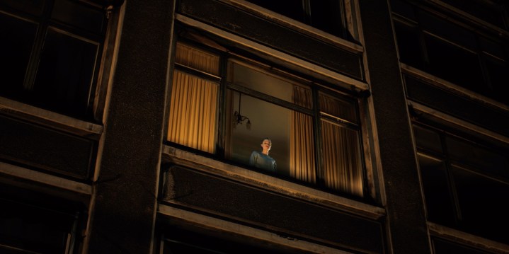 Maika Monroe peers out of a high window.