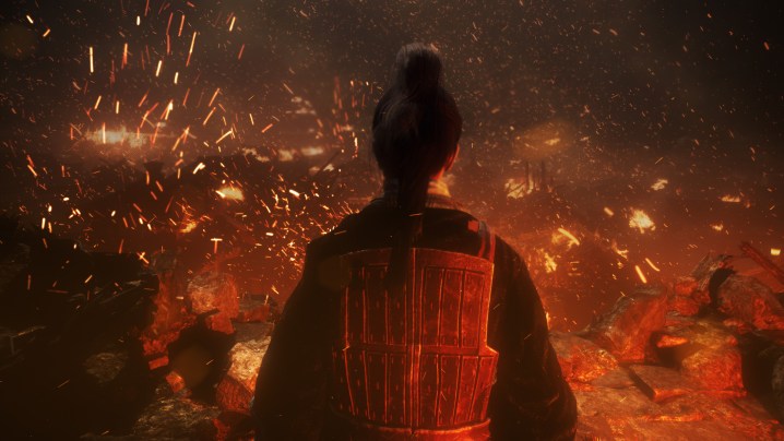 A soldier in red looks out over a burning village.