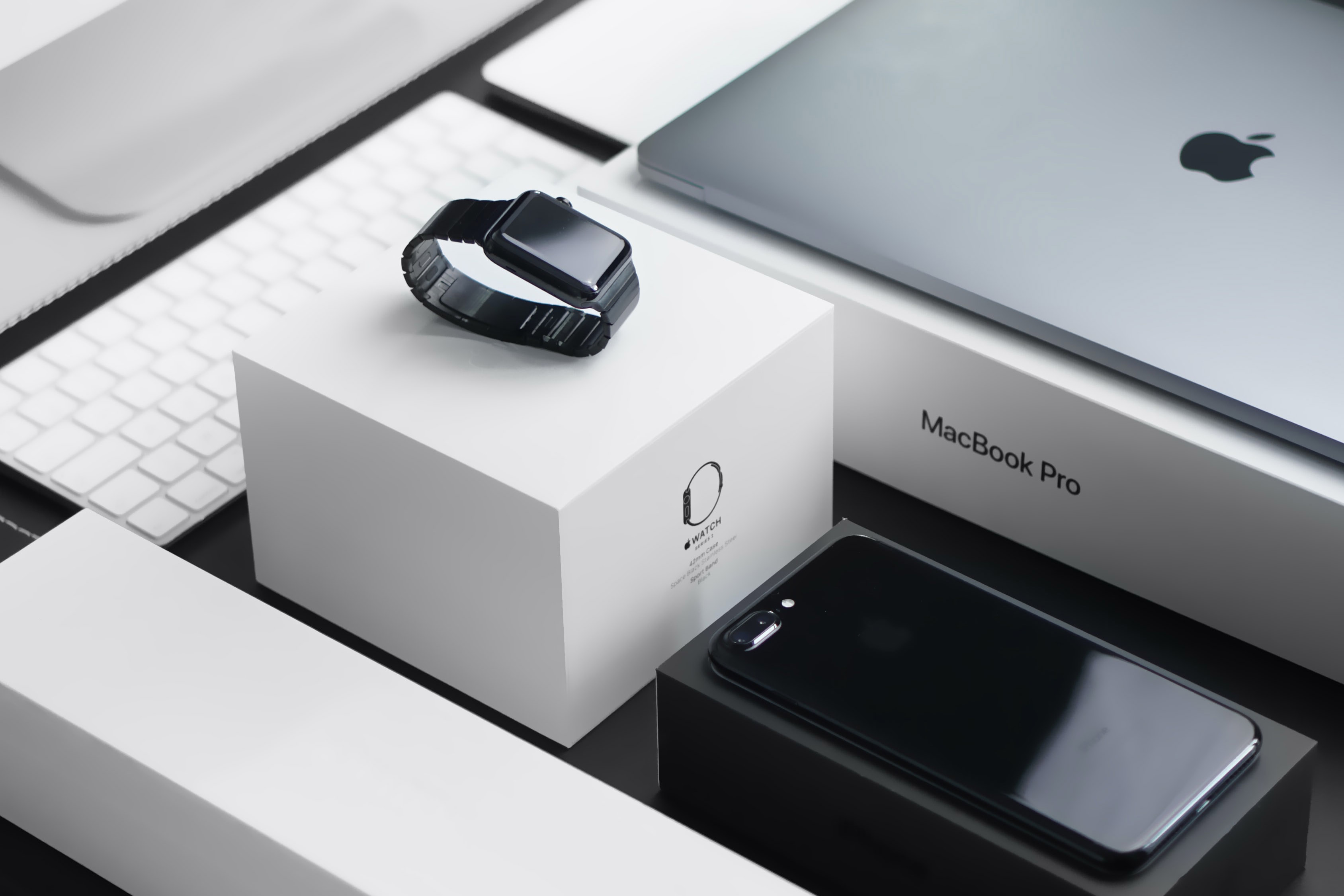 Um Apple Watch, iPhone e Macbook Pro sentados em uma mesa.