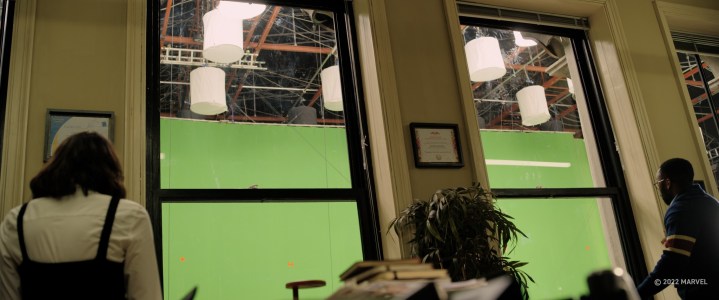 Le persone guardano fuori da una finestra in un edificio per uffici con uno schermo verde all'esterno in una scena di Doctor Strange in the Multiverse of Madness.