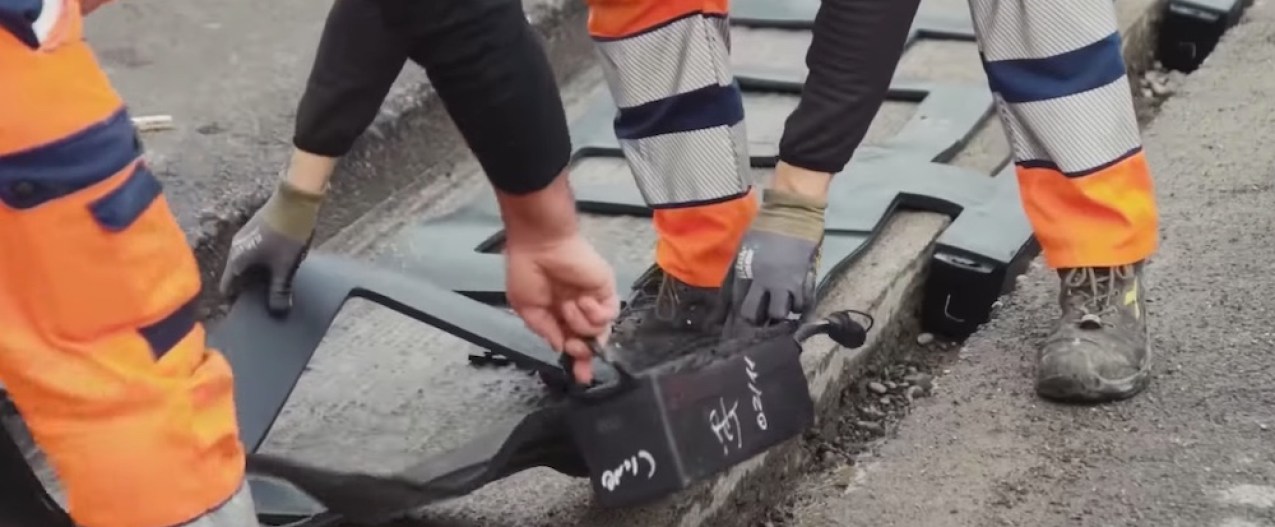 Workers building a road that charges electric vehicles wirelessly.
