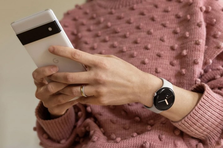 Lifestyle image of a woman wearing a Google Pixel Watch while typing on a Google Pixel 6 Pro.