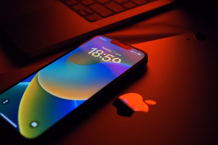 Un iPhone 13 Pro con iOS 16 si trova sopra un iPad con una luce rossa che brilla.