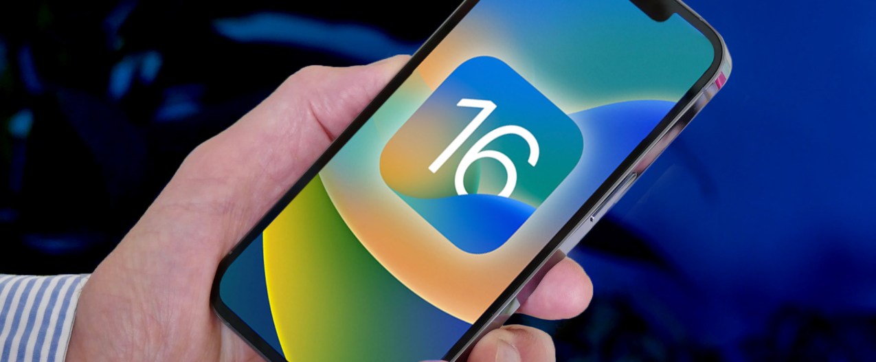 Man holds an iPhone 13 Pro with the iOS 16 logo on screen.