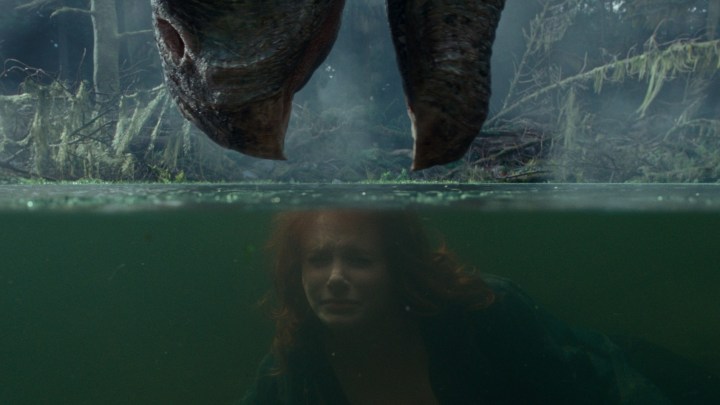 Bryce Dallas Howard's character tries to hide from a dinosaur in a lagoon in a scene from Jurassic World: Dominion.