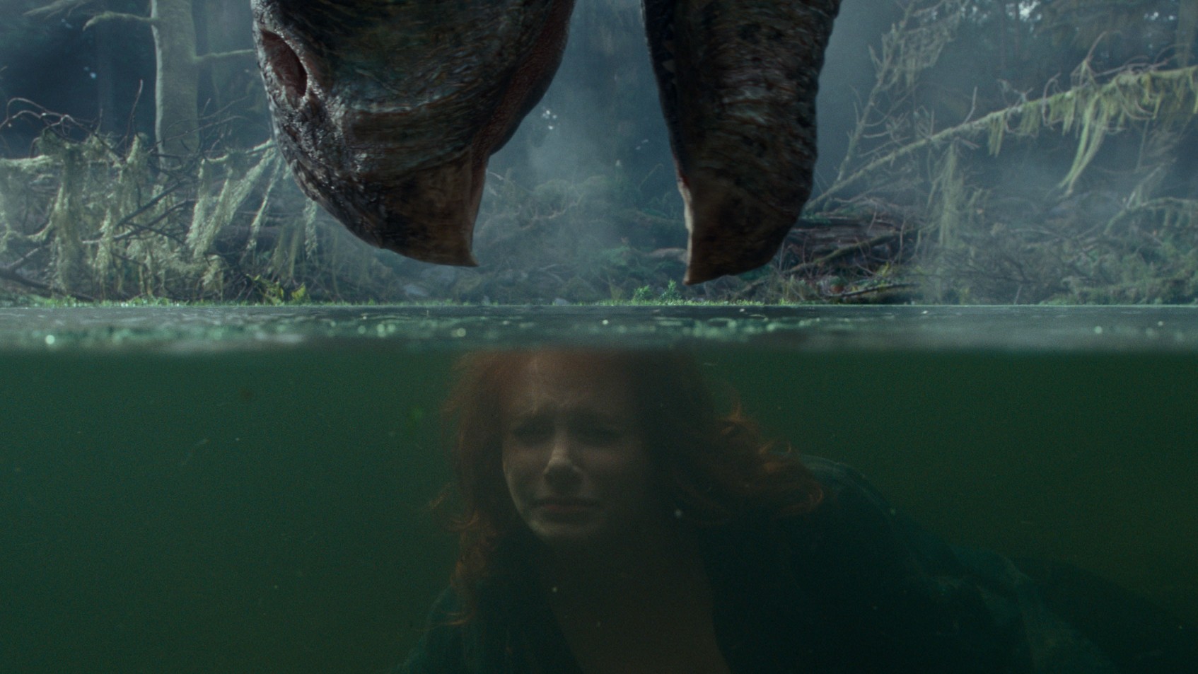 O personagem de Bryce Dallas Howard tenta se esconder de um dinossauro em uma lagoa em uma cena de Jurassic World: Dominion.