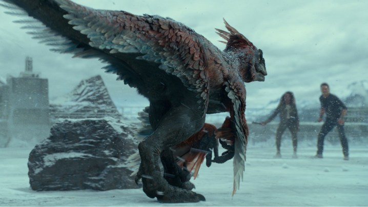 Un dinosauro si avvicina a due personaggi sul ghiaccio in una scena di Jurassic World: Dominion.