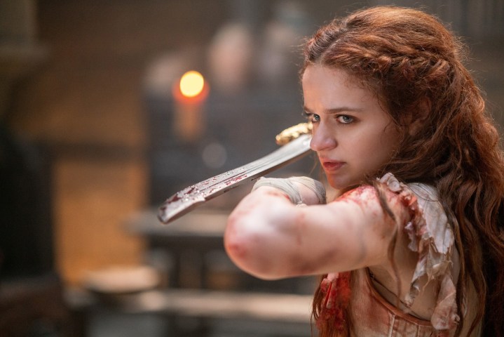 Joey King holds a sword at the readyin a scene from The Princess.