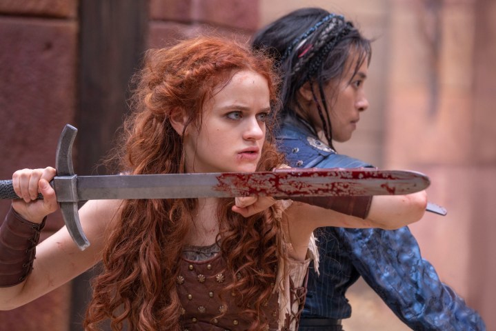 Joey King and Veronica Ngo stand back to back with swords in a scene from The Princess.