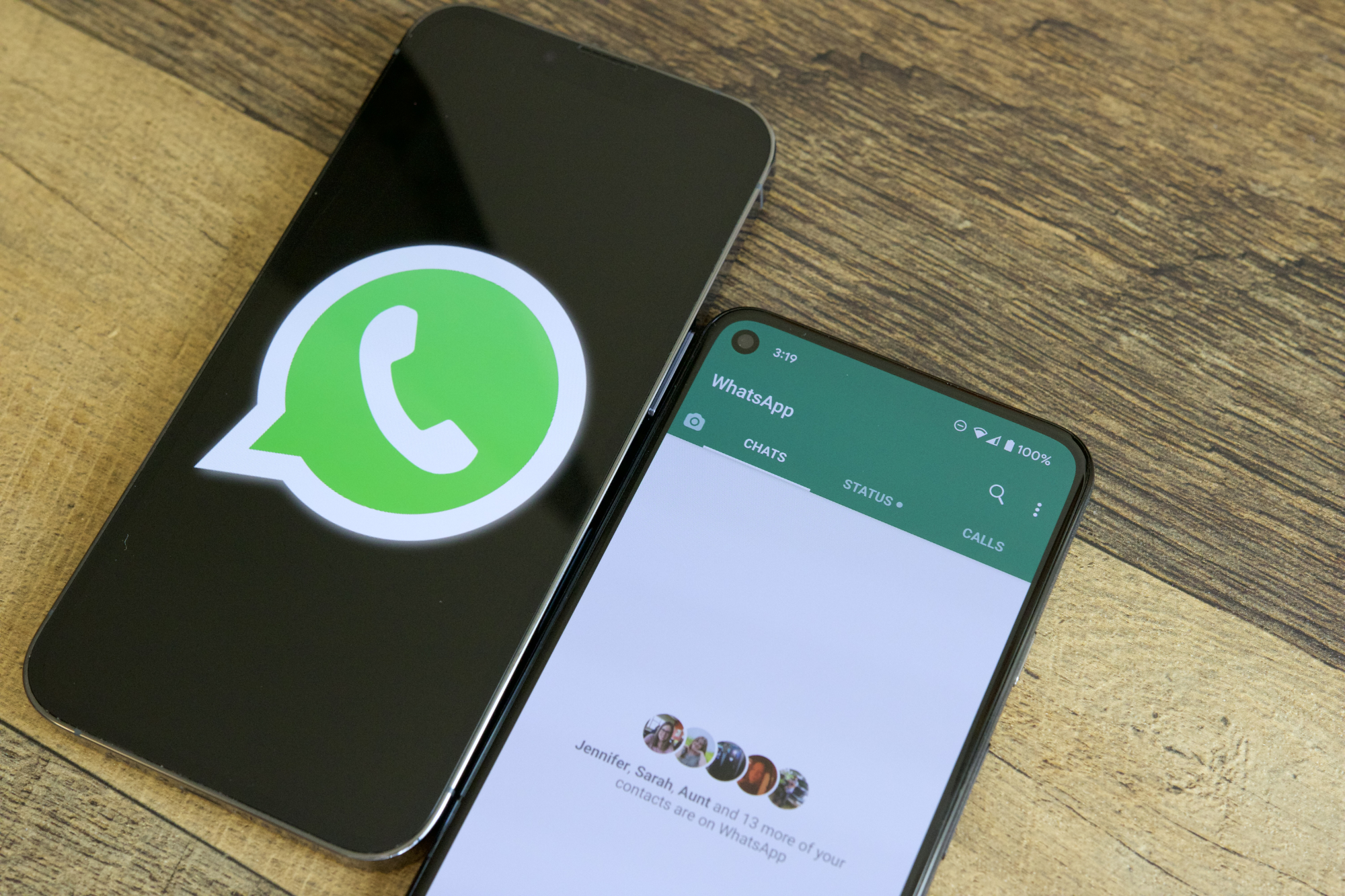 Two phones on a table next to each other. One is showing the WhatsApp logo, and the other is running the WhatsApp application.