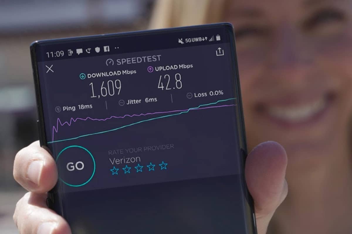 Mulher segurando smartphone com resultados de teste de velocidade na rede Verizon 5G Ultra Wideband.