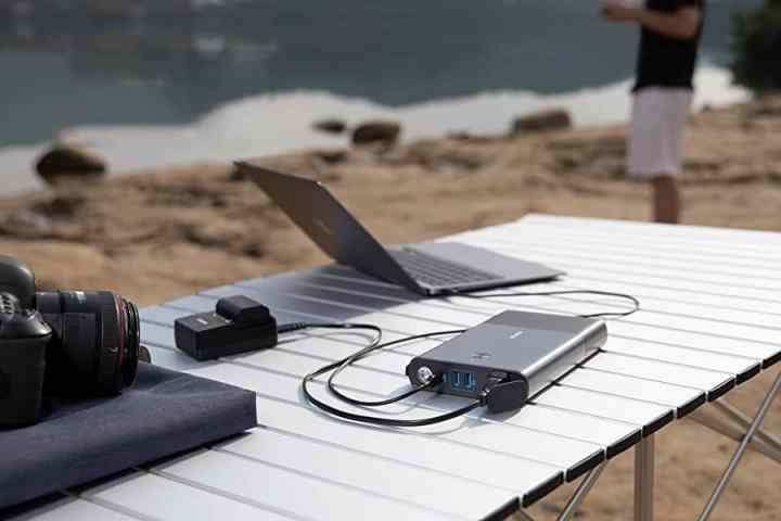 Anker Powerhouse 511 Portable Charger powering laptop on a table at the beach.