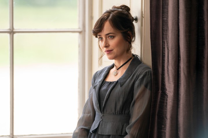 Anne Elliot se tient près d'une fenêtre et se drape dans Persuasion de Netflix.